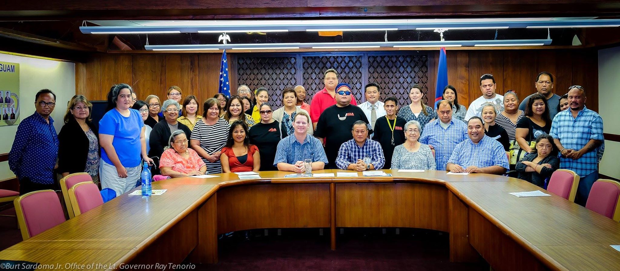 Large group poses for photo in Governor's conference room.