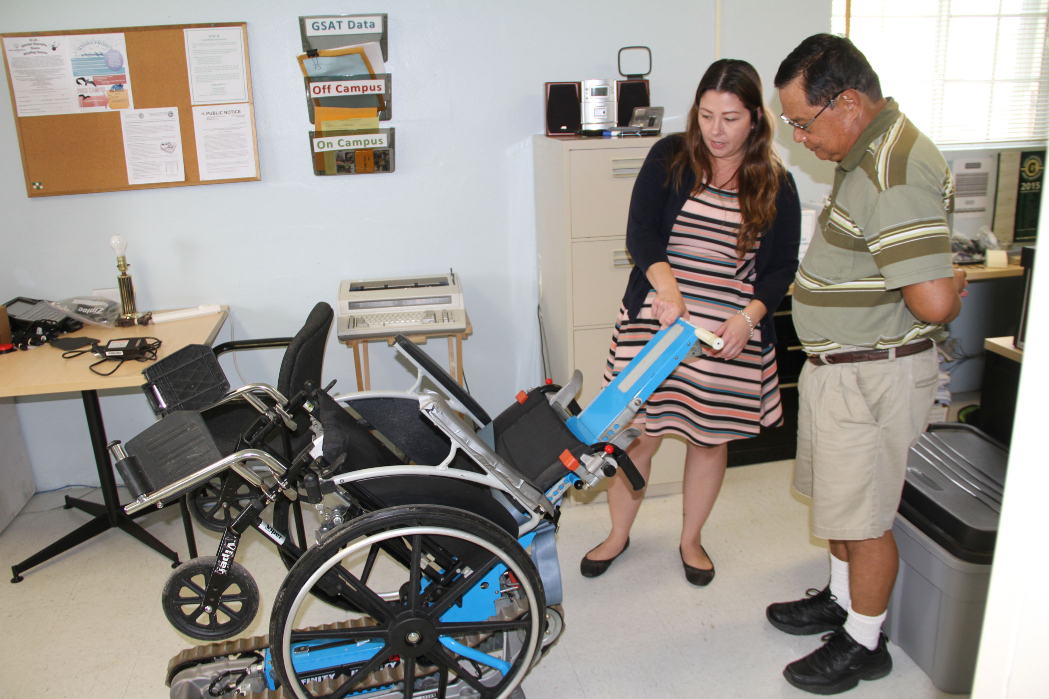 Two individuals looking at assistive technology device.