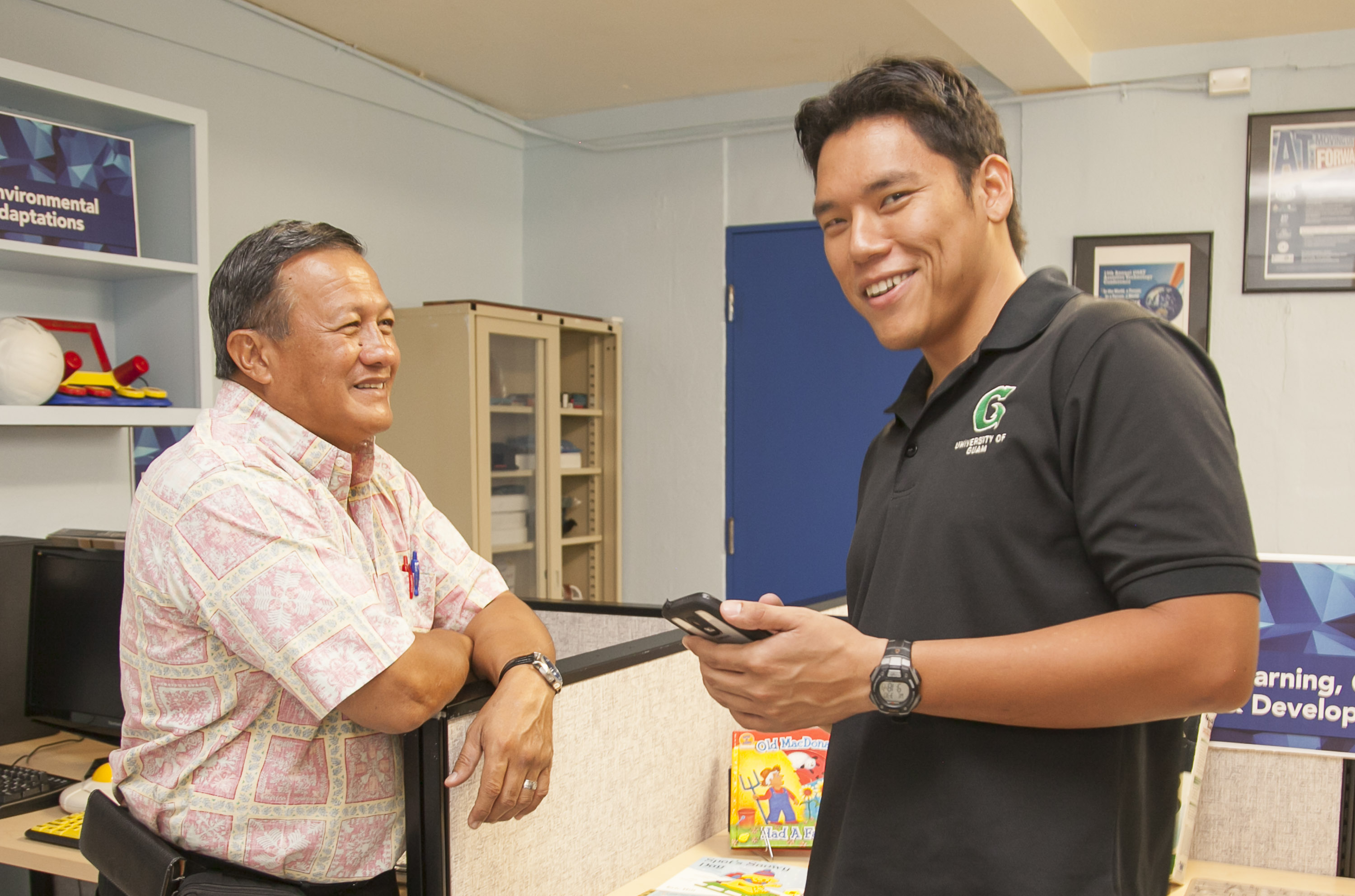 Ben Servino (left), Director of the Department of Integrated Services for Individuals with Disabilities (DISID), and Andrew Gumataotao, University of Guam student (right), share a laugh during the Open House.