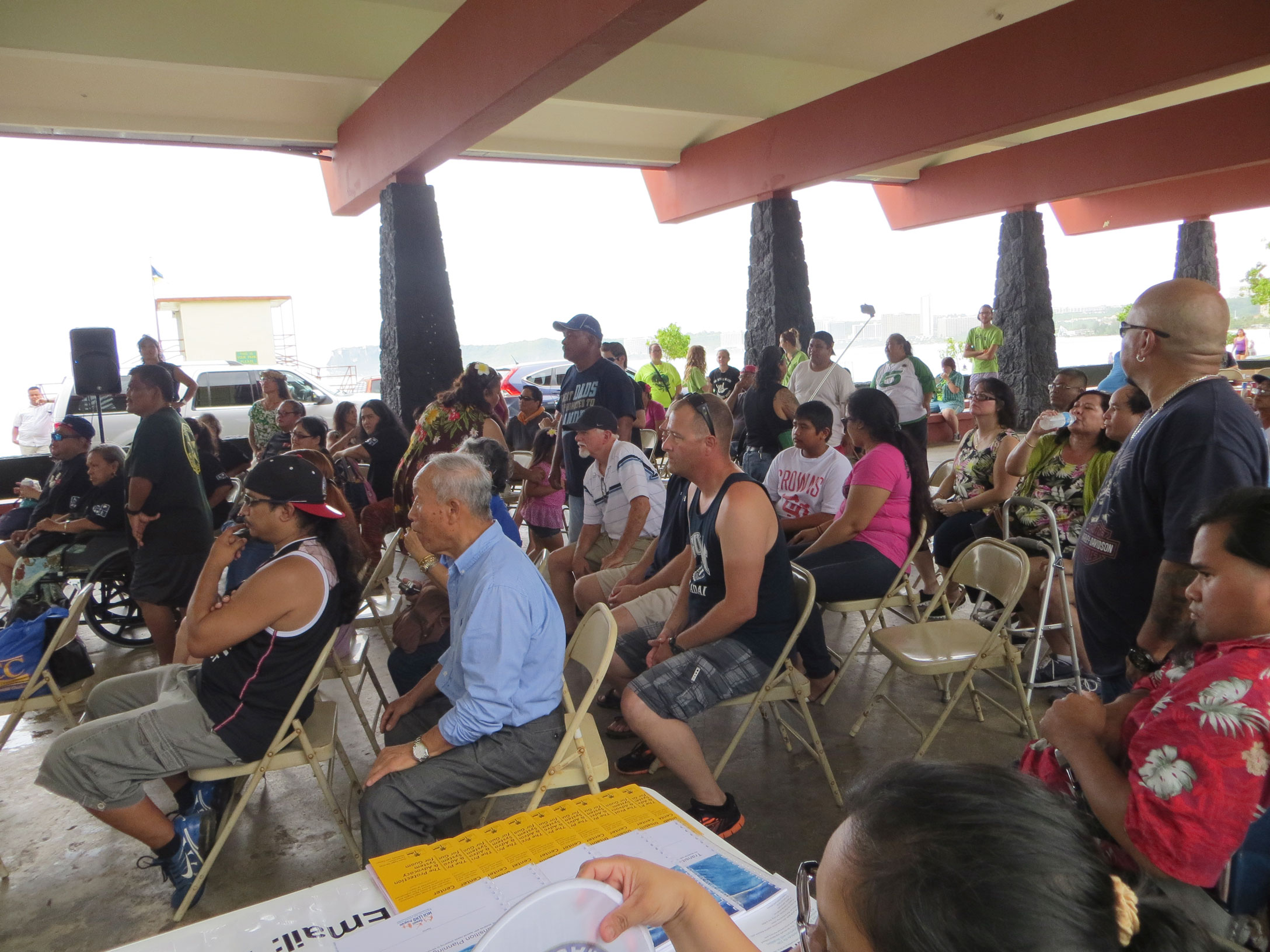 Crowd of participants seated under outdoor pavilion.