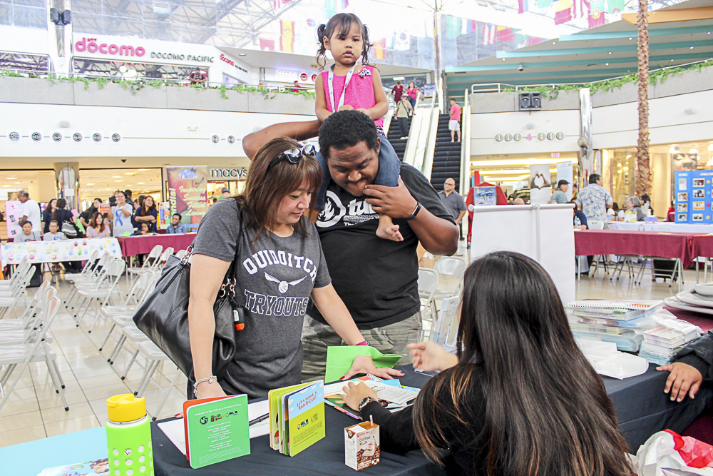 Christina Jung, Guam CEDDERS Training Associate (seated), shares information with parents on the Guam Early Hearing Detection and Intervention (EHDI) program during the DPHSS Healthy Mothers, Healthy Babies Fair, at the Micronesia Mall on January 7.