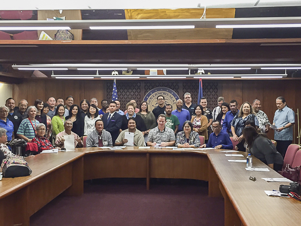 Attendees of the NDEAM Proclamation Signing pose for a photo with Acting Governor Ray Tenorio.